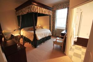 Worsley Arms Hotel في Hovingham: غرفة نوم مع سرير بأربعة أعمدة مع مظلة