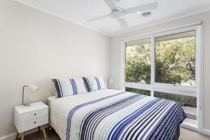 a white bedroom with a bed and a window at Serenity on Tarakan - quiet location near bay in Sorrento