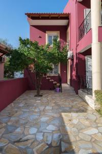 a pink house with a tree in the courtyard at Cosy 3bedroom Apartment in Sami
