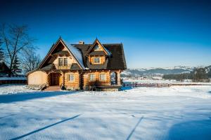 a large wooden house in the snow with snow at Domek Góralski in Poronin