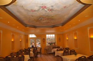 a dining room with tables and chairs and a painting on the ceiling at Hotel Paseo in Aachen