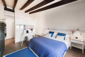 a white bedroom with a blue bed and a desk at Victoria Site-Mercat Central in Valencia