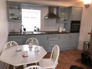 a kitchen with a white table and chairs and a sink at The Stables Holiday Cottage No 9 in Woodstown