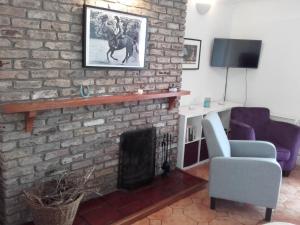 a living room with a brick fireplace with a horse picture at The Stables Holiday Cottage No 9 in Woodstown