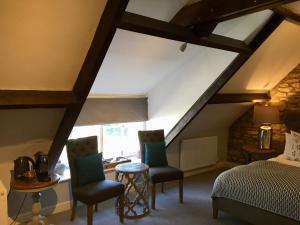 a attic bedroom with a bed and two chairs at The Sheep on Sheep Street Hotel in Stow on the Wold
