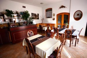 Un comedor con mesas y sillas y una cocina. en Keszi Panzió, en Budakeszi