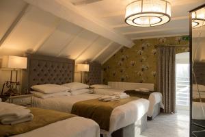 a bedroom with three beds and a chandelier at Leighinmohr House Hotel in Ballymena