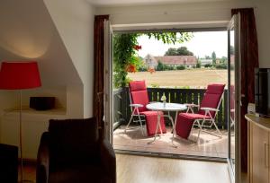 a patio with red chairs and a table on a balcony at Ferienhaus Kur & Golf in Bad Windsheim