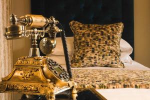 a gold phone on a table next to a bed at Leighinmohr House Hotel in Ballymena