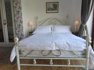 サドベリーにあるMill House Bed & Breakfastの白いベッド(金属製フレーム付)が備わるベッドルームです。