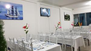 a room with white tables and chairs and a ship on the wall at Tropical Resort Tocaima in Tocaima