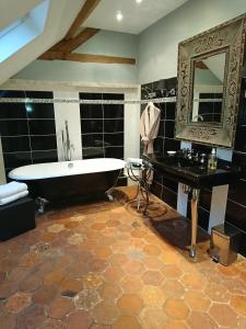 La grande salle de bains est pourvue d'une baignoire et d'un miroir. dans l'établissement Côté Jardin - Chambres d'hôtes, à Senlis