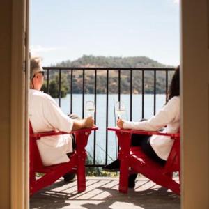 Dos personas sentadas en una mesa en un balcón con bebidas en Clear Lake Cottages & Marina, en Clearlake