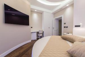 una camera con un grande letto e una TV a schermo piatto a parete di LUX Suites in Roma a Roma