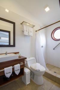 a bathroom with a toilet and a sink and a tub at Hotel Volcano in Puerto Villamil