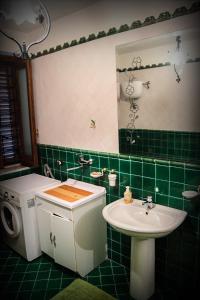 un bagno piastrellato verde con lavandino e lavatrice di Il Vigneto a Tramonti