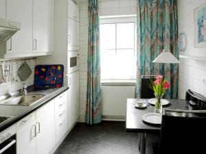 eine Küche mit einem Waschbecken, einem Tisch und einem Fenster in der Unterkunft Sonnige Ferienwohnung am Meer in Travemünde