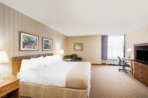 a hotel room with a large bed and a television at Ramada by Wyndham Watertown Thousand in Watertown