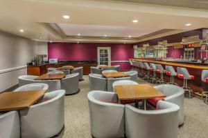 a restaurant with tables and chairs and a bar at Ramada Plaza by Wyndham Garden Grove/Anaheim South in Anaheim