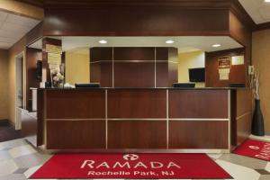 a reception desk in a hotel lobby with a red rug at Ramada by Wyndham Rochelle Park Near Paramus in Rochelle Park