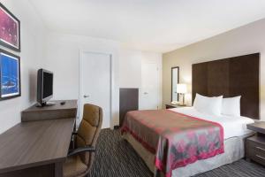 a hotel room with a bed and a desk at Ramada by Wyndham Monterey in Monterey