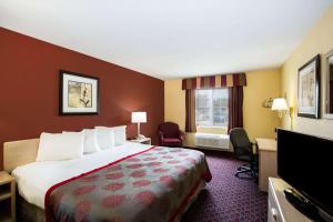 a hotel room with a bed and a flat screen tv at Ramada by Wyndham Sioux Falls in Sioux Falls