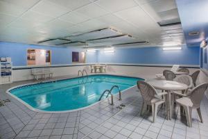 a pool in a room with a table and chairs and a table and a table at Ramada by Wyndham Sioux Falls in Sioux Falls