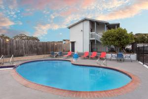 une grande piscine avec des chaises et une maison dans l'établissement Ramada by Wyndham Monterey, à Monterey