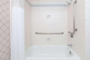 a bathroom with a shower with a white tub at Ramada by Wyndham Hawthorne/LAX in Hawthorne +12 photos