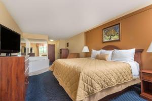 a hotel room with a bed and a flat screen tv at Ramada by Wyndham Catlettsburg Ashland in Catlettsburg