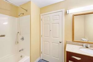 a bathroom with a white door and a sink at Ramada by Wyndham Kittery in Kittery