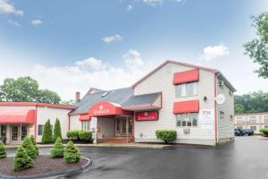 a mcdonalds restaurant with red awnings in a parking lot at Ramada by Wyndham Groton in Groton