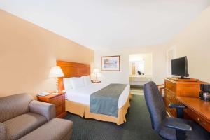 um quarto de hotel com uma cama e duas cadeiras em Ramada by Wyndham Flagstaff East em Flagstaff