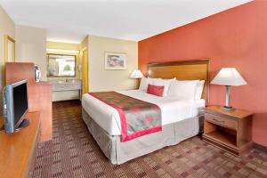 ein Hotelzimmer mit einem Bett und einem TV in der Unterkunft Ramada by Wyndham Baltimore West in Catonsville