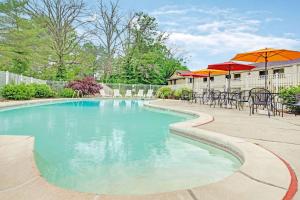 una piscina con mesas, sillas y sombrillas en Ramada by Wyndham Flemington, en Flemington