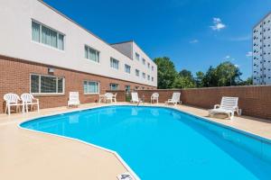 einen Pool mit Stühlen und ein Gebäude in der Unterkunft Ramada by Wyndham Paintsville Hotel & Conference Center in Paintsville