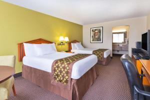 a hotel room with two beds and a television at Ramada by Wyndham Pikesville/Baltimore North in Pikesville