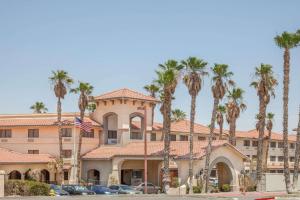 Un edificio con palmeras delante. en Ramada by Wyndham Barstow, en Barstow