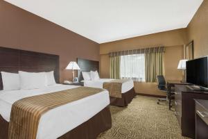 a hotel room with two beds and a television at Ramada by Wyndham Paintsville Hotel & Conference Center in Paintsville
