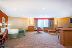 Habitación de hotel con cama y sala de estar. en Ramada by Wyndham Des Moines Tropics Resort & Conference Ctr en Urbandale