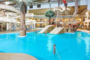 a large indoor water park with a slide and swings at Ramada by Wyndham Des Moines Tropics Resort & Conference Ctr in Urbandale