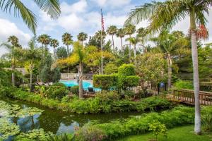 a pool in a garden with palm trees at Ramada by Wyndham Santa Barbara in Santa Barbara