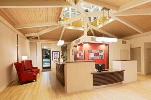 a lobby with a reception desk and a red chair at Ramada by Wyndham Santa Barbara in Santa Barbara