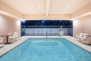 uma piscina com duas cadeiras e uma mesa em Ramada by Wyndham Fresno Northwest em Fresno