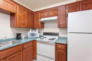 eine Küche mit Holzschränken und einem weißen Kühlschrank in der Unterkunft Ramada by Wyndham Fresno Northwest in Fresno