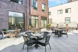 um pátio exterior com mesas, cadeiras e janelas em Ramada by Wyndham Flushing Queens em Queens