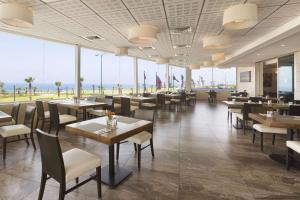 内坦亚Ramada Hotel & Suites by Wyndham Netanya的一间有桌椅、可欣赏海景的餐厅