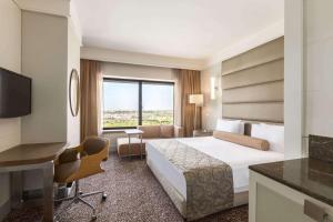 Ramada Plaza By Wyndham Istanbul Tekstilkent في إسطنبول: غرفة فندقية فيها سرير ومكتب وكمبيوتر