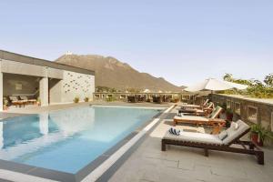 una piscina con tumbonas y un hotel en Ramada Udaipur Resort & Spa, en Udaipur