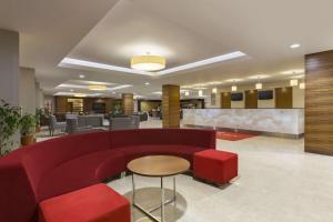 a lobby with a red couch and a table and chairs at Ramada Resort by Wyndham Akbuk - All Inclusive in Didim